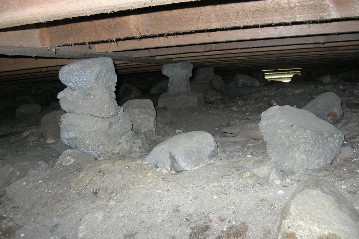 Through the small access opening, you can see the stone piles supporting the floor beams.