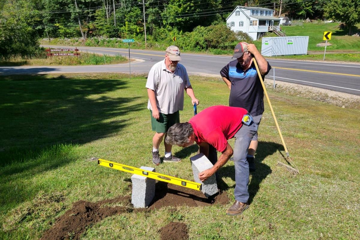 September 18, 2021 - A granite bench in memory of west Center Harbor resident Dave Reilly (1946-2021) is being installed on the Town House grounds.