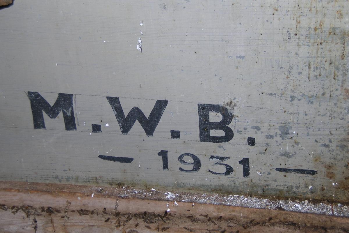 The original sign was hand-lettered by "M.W.B." in 1931. His mark was found on the back of the sign.