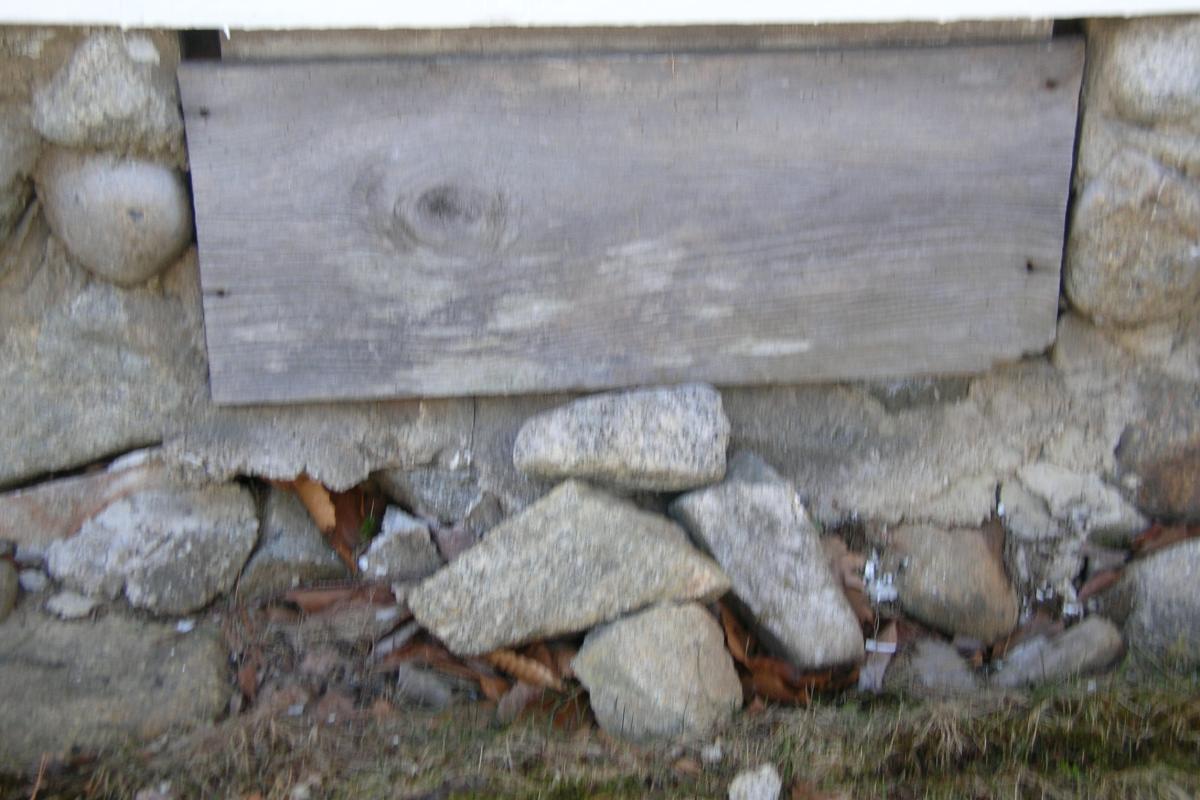 This wooden louvered vent in the north wall of the foundation north had rotted away years ago and was covered with a board.